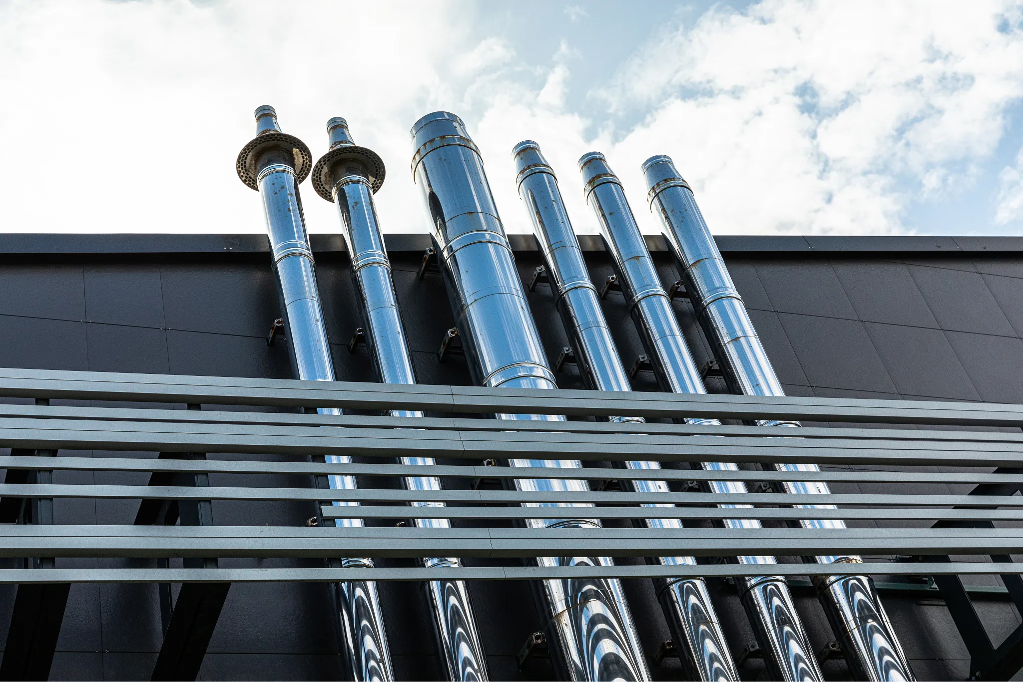 a-lot-of-metal-pipes-stick-out-of-a-large-building-2025-02-12-04-56-23-utc 1