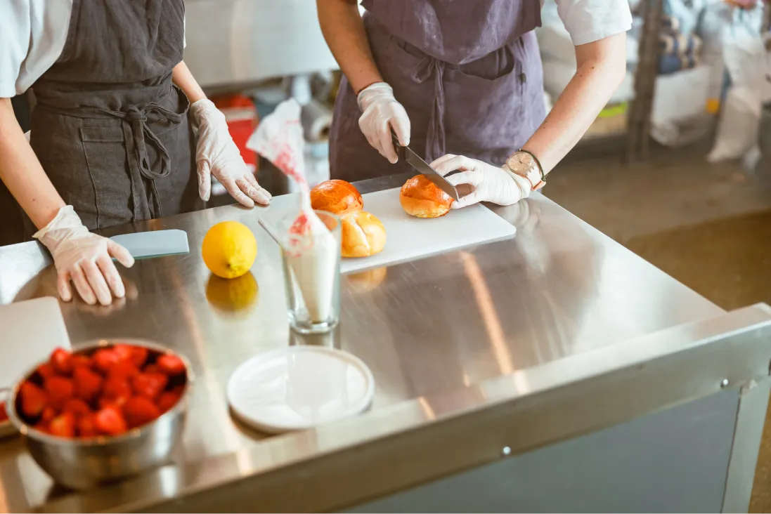 employee-cuts-bun-while-colleague-stands-at-table-2025-03-24-10-16-29-utc 1